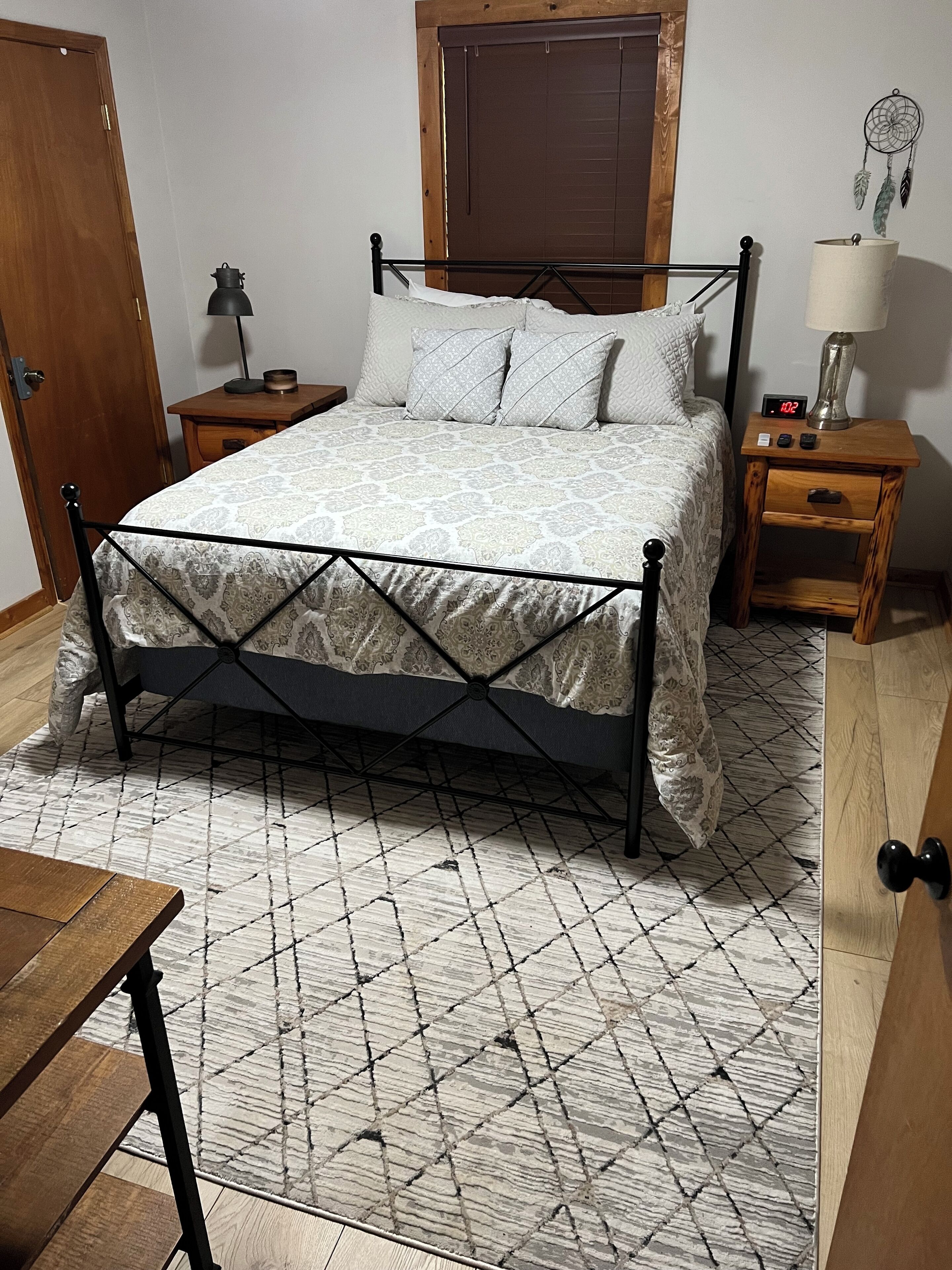 Une chambre à coucher avec un lit, une table de chevet, une lampe, une horloge et une porte en bois.
