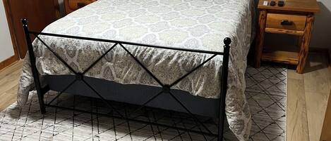 Une chambre à coucher avec un lit, une table de chevet, une lampe, une horloge et une porte en bois.