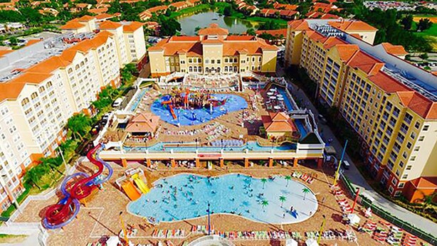 A resort with multiple buildings, a central pool area, and a water slide.