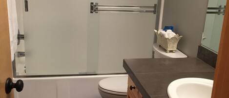 A bathroom with a shower, toilet, and sink.