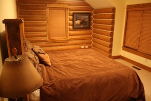 Cozy cabin-style bedroom with a large bed, wooden logs, and a rustic touch.