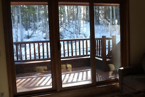 Enjoy the serene views from the deck, featuring a comfortable bench and chair, overlooking the surrounding trees.
