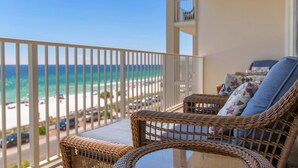 A balcony with wicker furniture and a view of the beach.