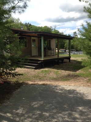 Eine kleine Holzhütte mit Veranda, Tür und Fenster.