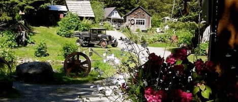 Een landweg met een oldtimer, een watermolen en huizen op de achtergrond.