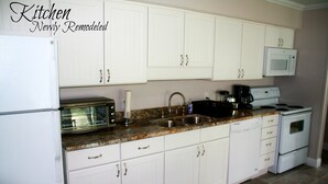 A kitchen with white cabinets, a granite countertop, a microwave, a stove, and a dishwasher.