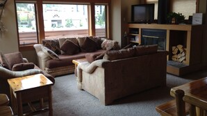 Ein gemütliches Wohnzimmer mit einer Couch, zwei Holzstühlen, einem kleinen Tisch, einem Kamin und einem Fernseher.