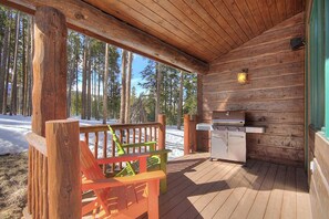 Eine Holzhütte mit einer Terrasse, einem Grill und einer Bank.