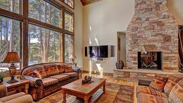 A spacious living room with a stone fireplace, large windows, and a cozy sofa set.