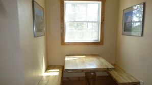 A room with a wooden table and benches, a window, and framed pictures on the walls. - Laramie Bluffs Mountain Getaway (Custer)