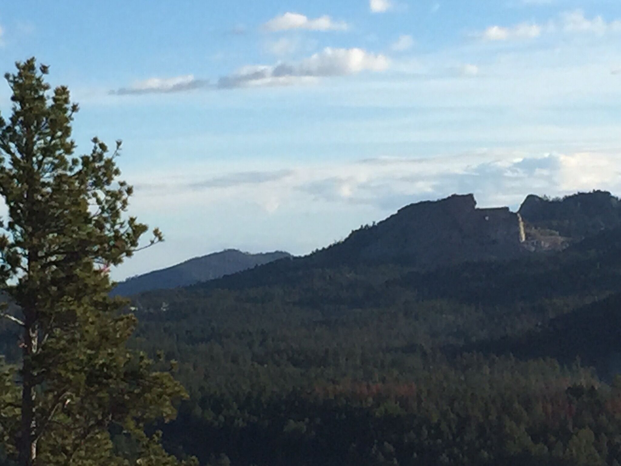 A mountainous landscape with a prominent rocky outcrop and dense forest.