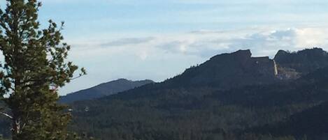 A mountainous landscape with a prominent rocky outcrop and dense forest.