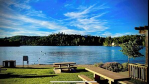 Blick auf einen See mit Picknicktischen und einer Holzterrasse.