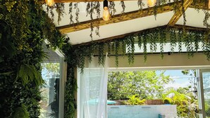 Un patio intérieur accueillant, agrémenté d’une végétation luxuriante, doté d’un espace salon confortable et offrant une vue sur une piscine.
