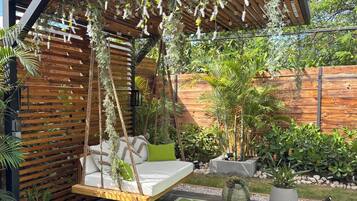 Ein moderner Außenbereich mit Sitzgelegenheiten, einer Schaukelstuhlsitzgruppe, einer Holz-Pergola und verschiedenen Topfpflanzen.