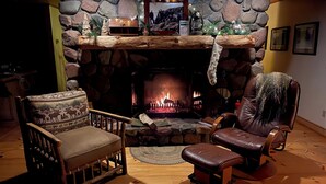 A cozy living room with a stone fireplace, two leather armchairs, and a wooden coffee table. - LUTSEN LAKEHOUSE on LAKE SUPERIOR (Lutsen)