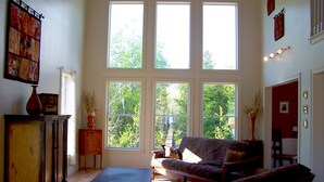 Ein geräumiges Wohnzimmer mit großen Fenstern, einem Sofa, einem Couchtisch und einem Kamin.