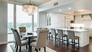 A modern kitchen with white cabinets, a central island, and a dining area with six chairs.