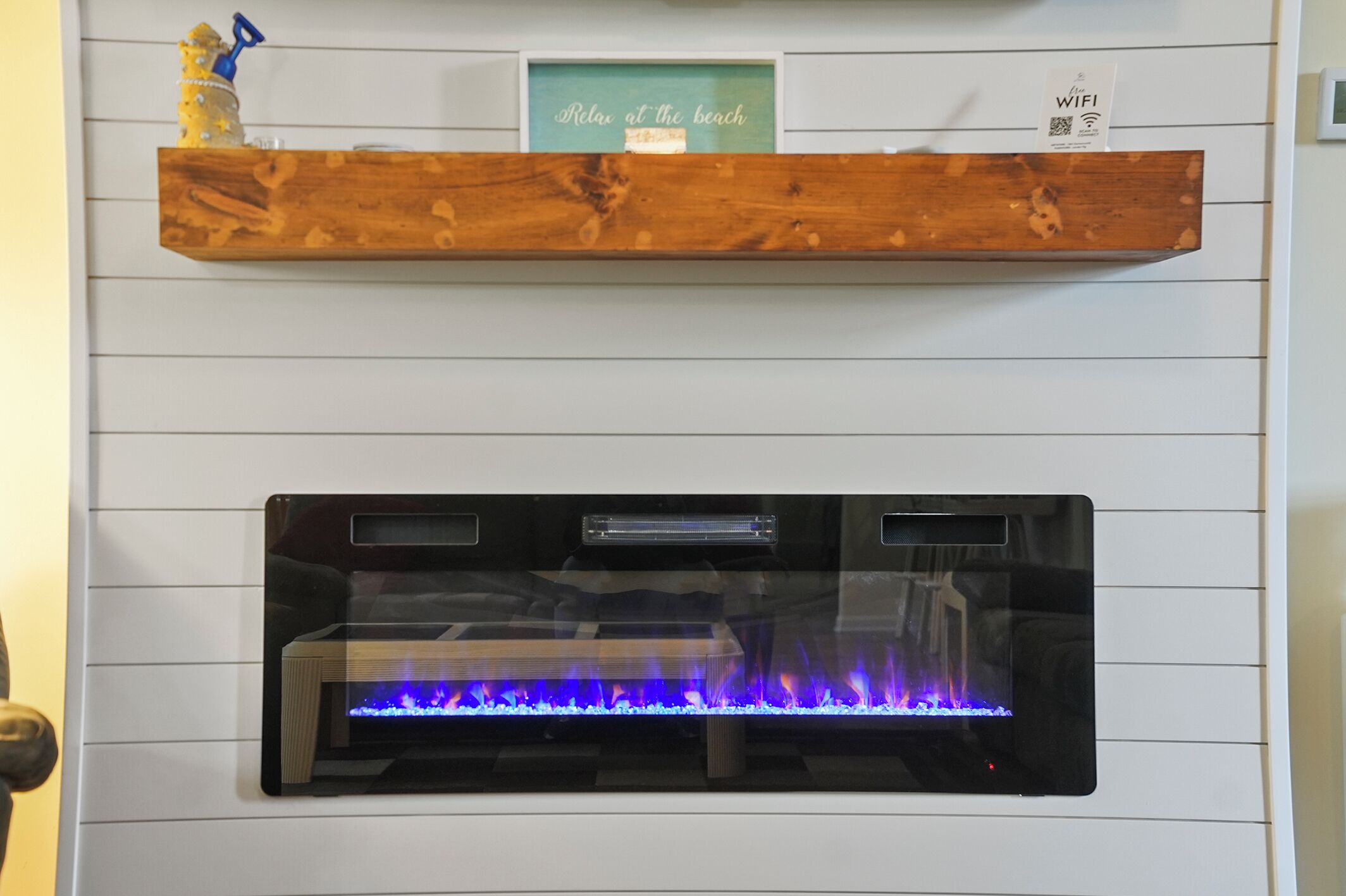 A fireplace with a visible fire, a wooden shelf above it, and a sign indicating WIFI availability.