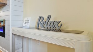 A reception desk with a 'Relax' sign, a WiFi sign, and a digital screen displaying a room. - 3BR Lewes Condo Near Beaches | 2 Kings + Screened Porch (Lewes)