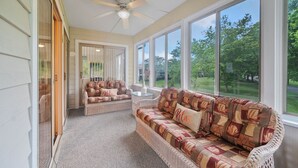A sunroom with wicker furniture, large windows, and a ceiling fan. - 3BR Lewes Condo Near Beaches | 2 Kings + Screened Porch (Lewes)