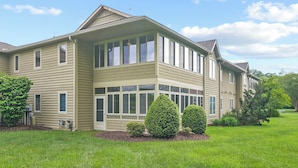 A two-story house with a large front porch, multiple windows, and a well-maintained lawn. - 3BR Lewes Condo Near Beaches | 2 Kings + Screened Porch (Lewes)