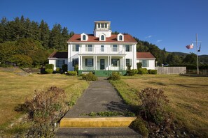 A large white two-story house with a green front porch, a central entrance, and a small tower-like structure on the roof. - Gorgeous, spacious, ONE BLOCK TO THE BEACH & pet friendly. Work + School WiFi! (Rockaway Beach)