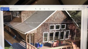Une maison dotée d’une terrasse en bois, d’un porche abrité et d’un escalier menant à l’entrée.