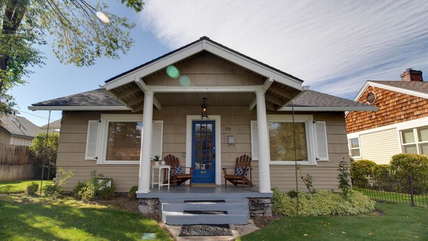 A two-story house with a blue front door, two wooden chairs on the porch, and a number 735 on the wall. - Hygge Harmony- Salt Hot Tub, 2 Fireplaces, 100+mbps Wifi, AC, Walk to Galveston! (Bend)