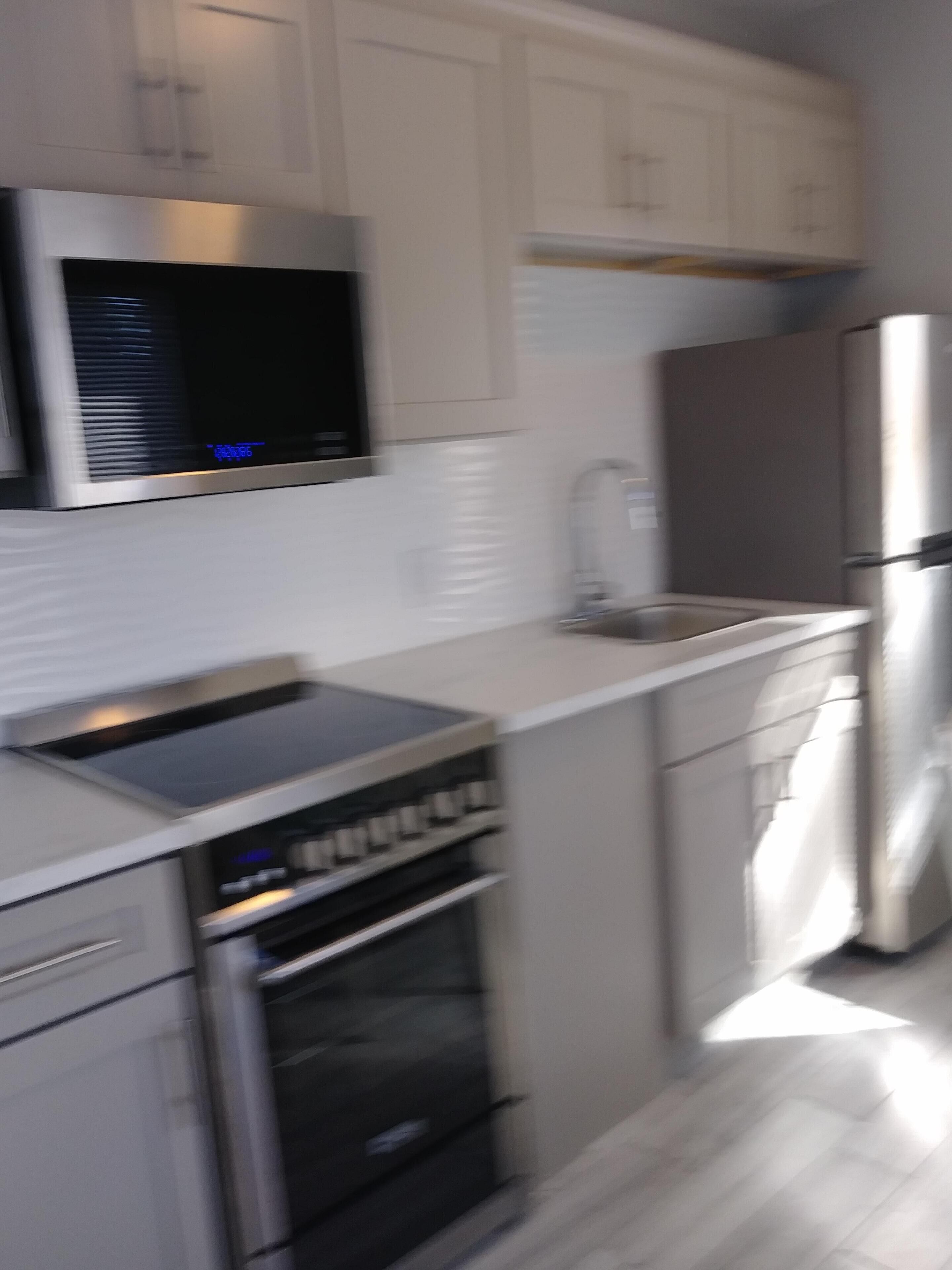 Eine moderne Küche mit Edelstahlgeräten, einem eingebauten Backofen und einer Mikrowelle über der Arbeitsplatte.