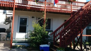 A building with a balcony, a staircase, and a blue cooler on the ground.