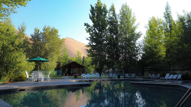 A swimming pool with lounge chairs and a gazebo in a wooded area. - Iconic Prospector Condo at Warm Springs (Ketchum)