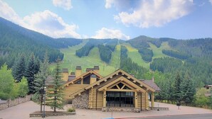 A log cabin-style building with a stone foundation, large windows, and a prominent front entrance. - Iconic Prospector Condo at Warm Springs (Ketchum)