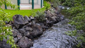 A rocky stream with a building in the background. - Iconic Prospector Condo at Warm Springs (Ketchum)