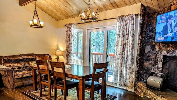 A cozy dining area with a wooden table and chairs, a sofa, and a fireplace. - Charming 3-Bedroom, 2-Bath Townhouse at Snow Summit Base – Ski, Hike, Relax! (BIG BEAR LAKE)