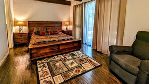 A bedroom with a wooden bed, a patterned rug, a sofa, and a large window with curtains. - Charming 3-Bedroom, 2-Bath Townhouse at Snow Summit Base – Ski, Hike, Relax! (BIG BEAR LAKE)