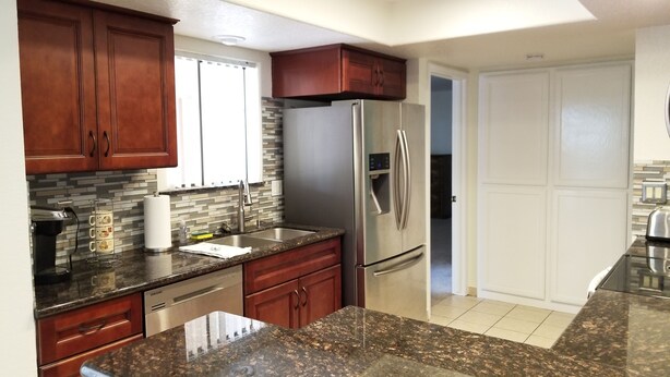 A modern kitchen with granite countertops, stainless steel appliances, and wooden cabinets.