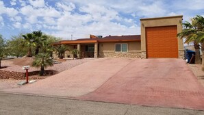 A single-story house with a red garage door, a stone foundation, and a paved driveway.