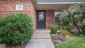 A brick house with a black front door, a number sign '8502', and a wreath on the door. - 5 ⭐️ Clean & Quiet Barstow Retreat (Amarillo)