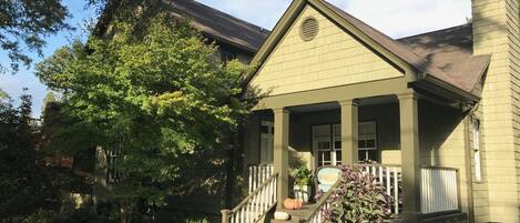 A two-story house with a front porch, a chimney, and a staircase leading to the entrance.