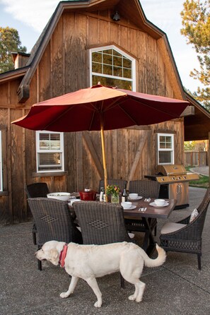 An outdoor patio with a wooden table, wicker chairs, and a red umbrella. - The Barn on Braden, Classic Splendor on the South Side  (Walla Walla)