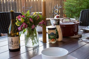 A table with a wine bottle, a vase of flowers, a jar of dressing, and a pot. - The Barn on Braden, Classic Splendor on the South Side  (Walla Walla)