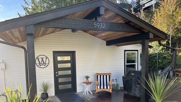 A building with a black door, a small porch with a chair, and a number 5932 on the roof.
