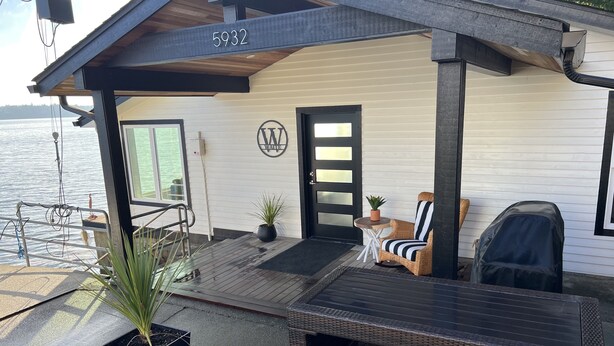 Une propriété située au bord de l’eau, dotée d’un patio couvert, d’un espace salon extérieur et offrant une vue sur l’eau.