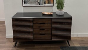 Une console moderne en bois foncé, surmontée d’un grand tableau abstrait, avec une petite plante en pot et un plateau posé sur le dessus.