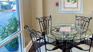 A glass-top table with four chairs, a framed botanical illustration on the wall, and a fire alarm sign. - Fall Steal! 129/nt base! Gulf front, Pool,Huge Balcony,Beach Supplies,VIEW! (Gulf Shores)