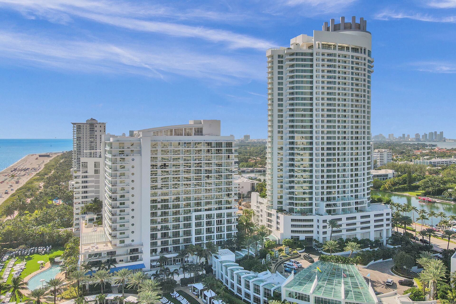 A high-rise hotel with multiple floors, a pool area, and a view of the beach and ocean.