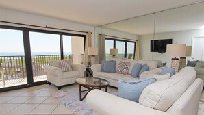 Ein geräumiges Wohnzimmer mit Balkon, ausgestattet mit zwei Sofas, einem Couchtisch und Lampen.