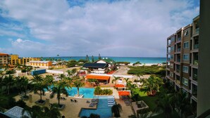 Een resort met een zwembad, palmbomen en uitzicht op de oceaan.
