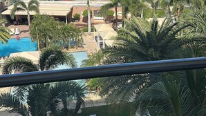 Een resort met een zwembad, palmbomen en uitzicht op de oceaan.